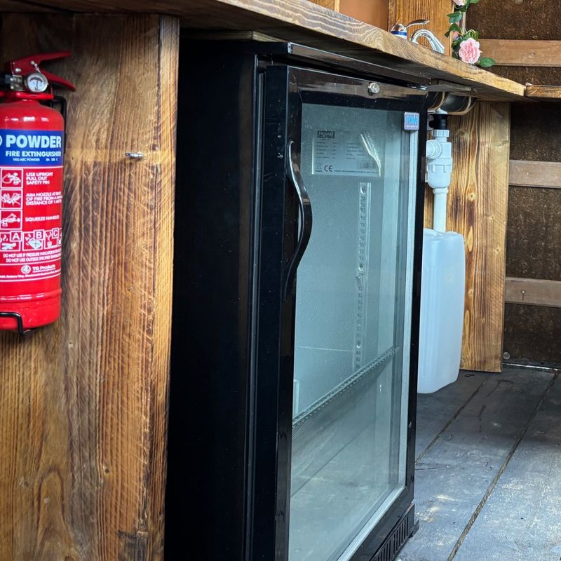 Glass-fronted under-counter drinks fridge inside the bar