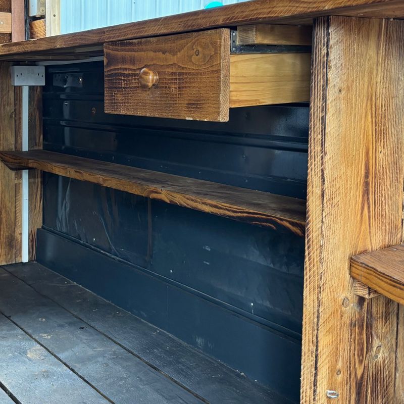 Wooden drawer, shelves and double socket behind the counter
