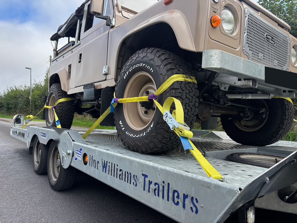 Close-up of ratchet straps securing a Defender's wheel to the trailer